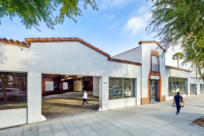 An architectural rendering shows a Spanish Revival-style storefront converted into a gallery space.