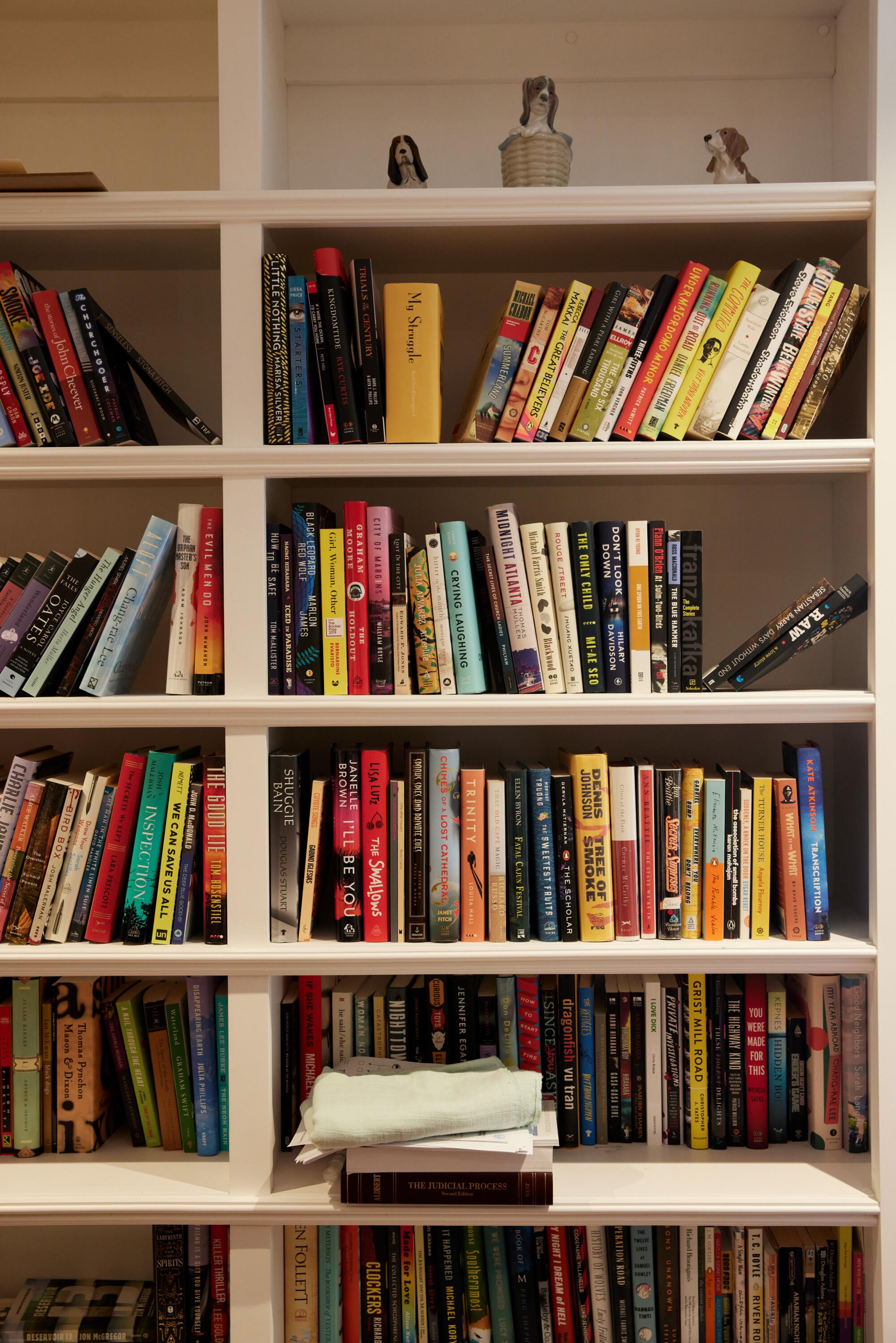 A detail of a white bookshelf with several colorful book spines. 