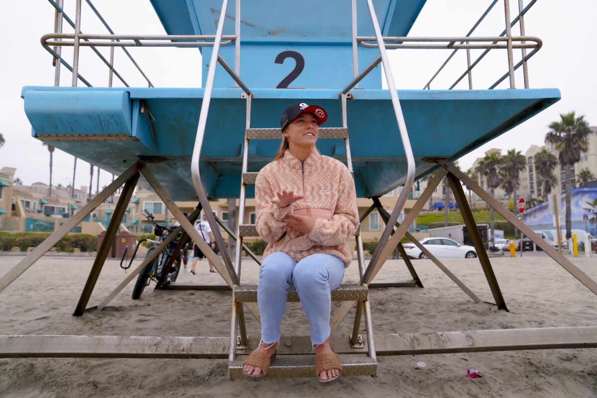 Alyssa Spencer, 18, of Encinitas, talks about her surfing career on a lifeguard tower near Oceanside Pier on Friday.  