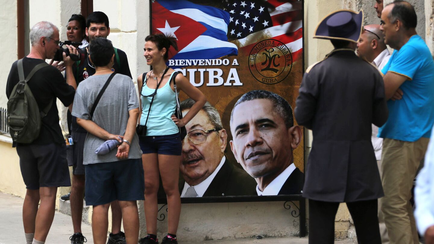 Tourists stand next to a sign showing President Obama, right, and Cuba President Raul Castro next to the Cathedral in Old Havana.