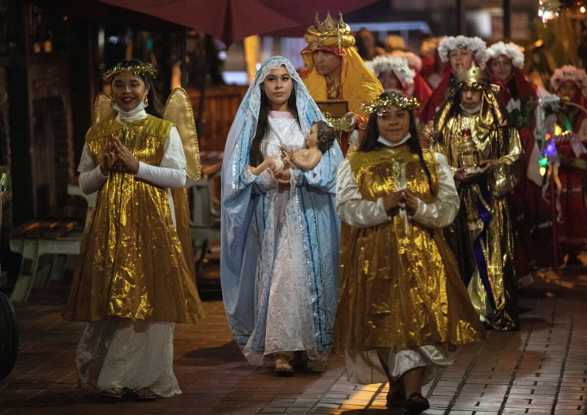 A person dressed as the Virgin Mary carrying a baby doll is flanked by others