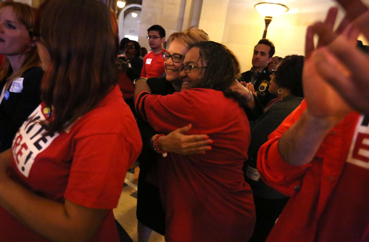 Maria Elena Durazo, president of the national labor organization Unite Here, embraces Alma Romero, a housekeeper, while celebrating the Los Angeles City Council's tentative agreement to raise the city's minimum wage to $15 per hour.