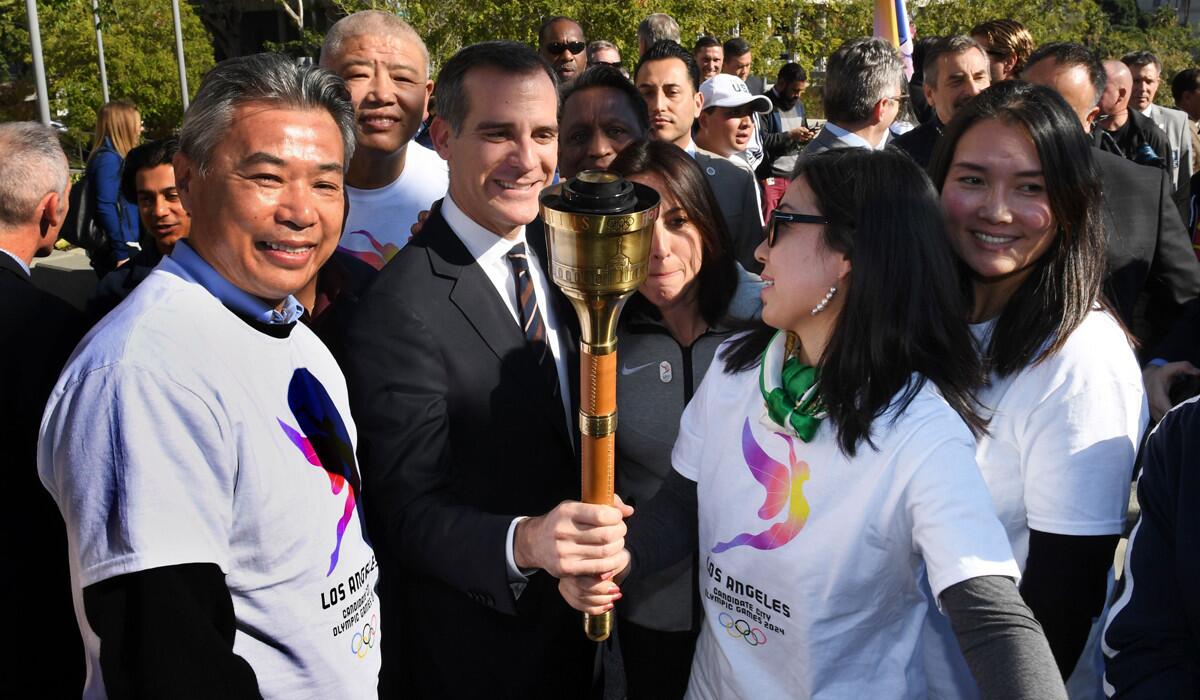 Los Angeles Mayor Eric Garcetti holds an Olympic torch from the 1984 Summer Games with former Chinese Olympians as they celebrate the L.A. City Council's 13-0 unanimous final approval vote to bid for the 2024 Games on Jan. 25.