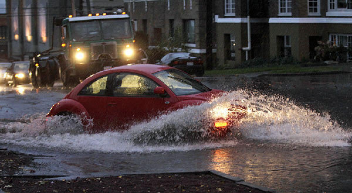Cars and trucks navigate through standing water Monday at an intersection in Tacoma, Wash.