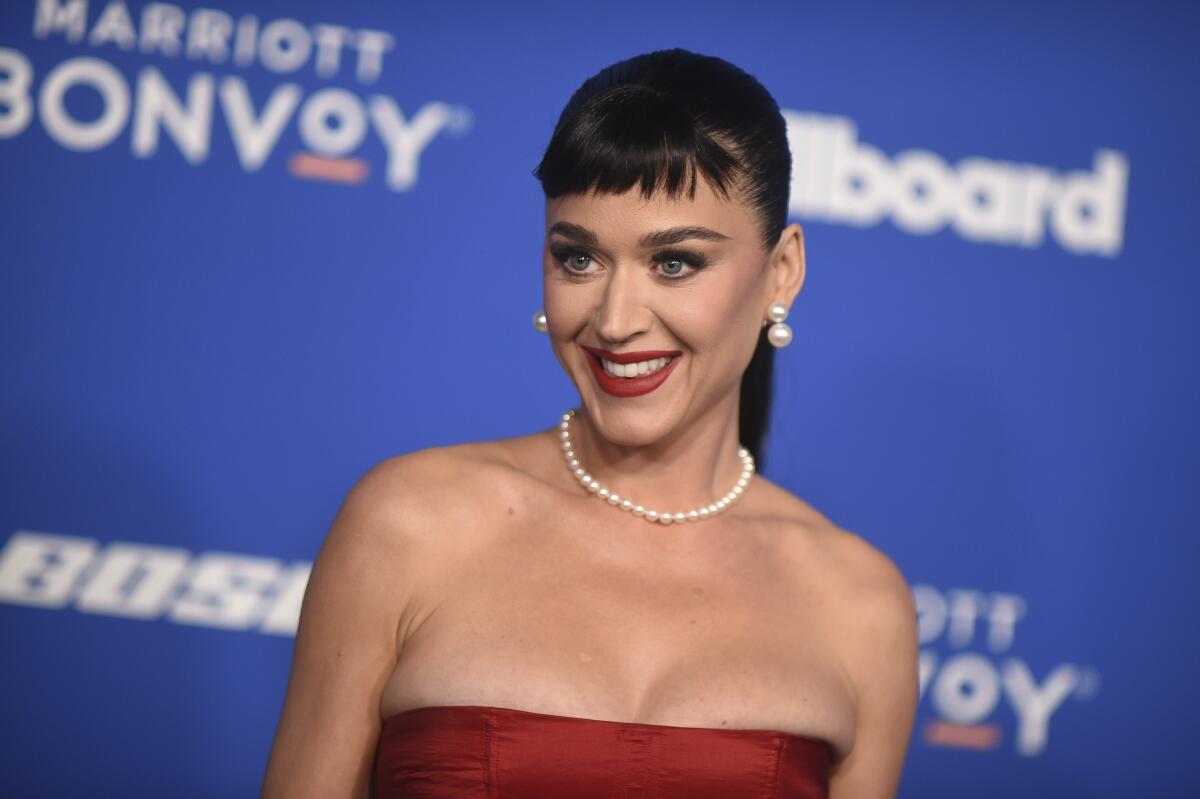 Katy Perry in a ponytail with bangs, a pearl necklace and a red strapless gown