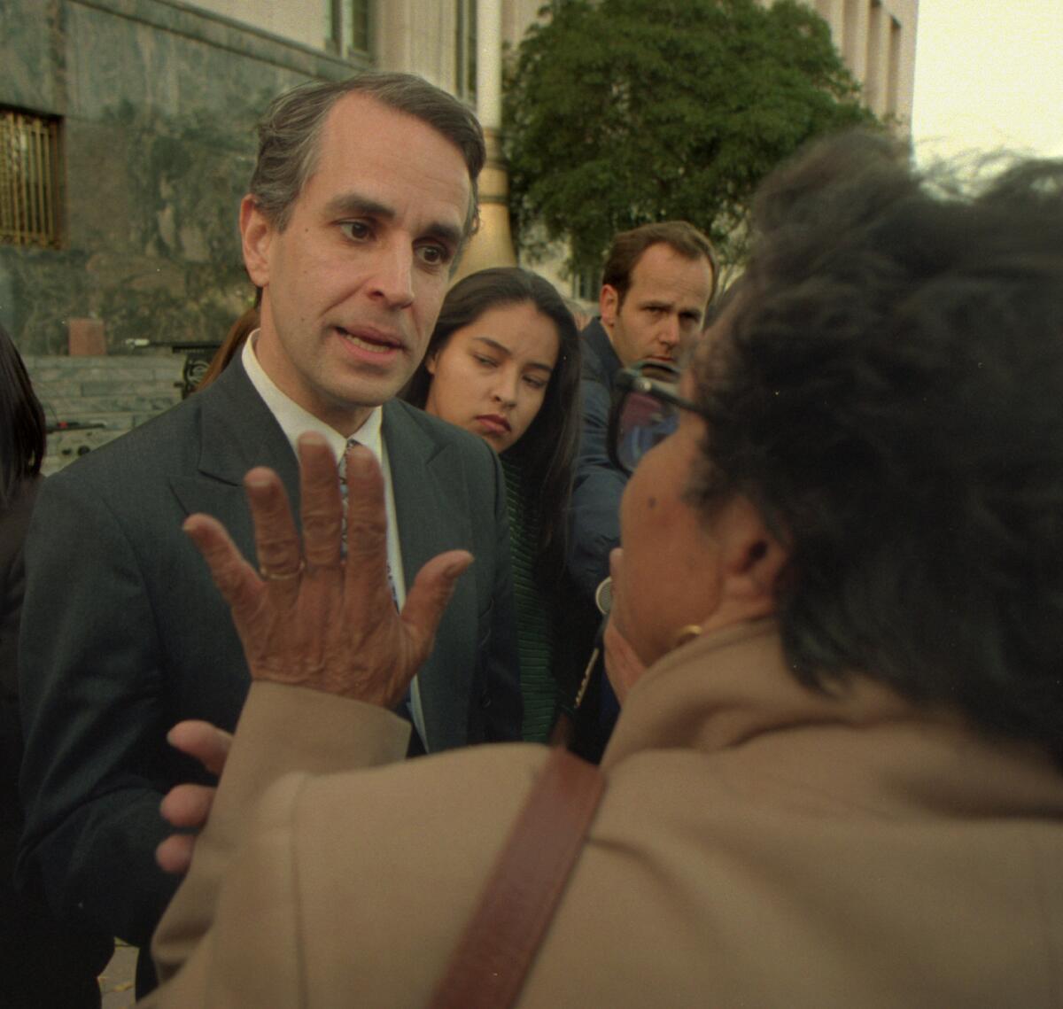 Ron Prince, the spark behind what became Proposition 187, argues with a woman about the controversial initiative as members of the media look on.