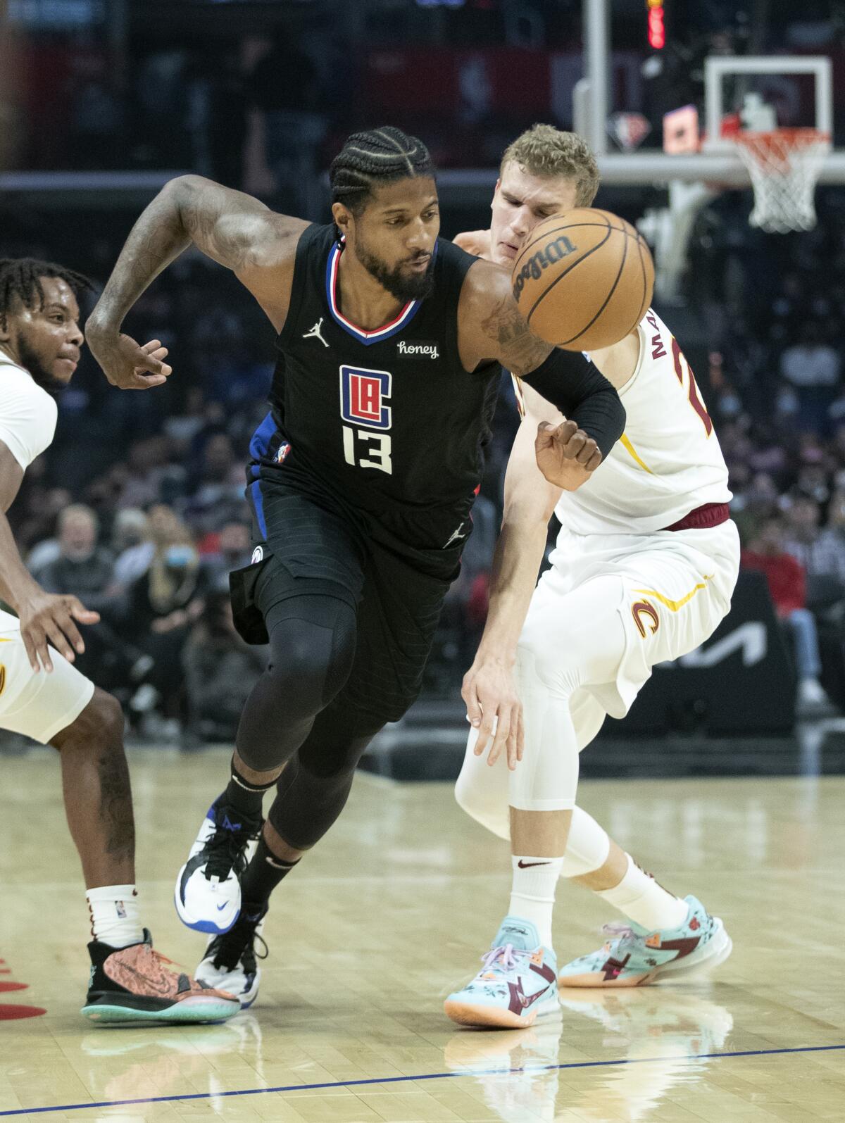 Clippers guard Paul George drives to the basket past Cleveland Cavaliers guard Darius Garland and forward Lauri Markkanen.