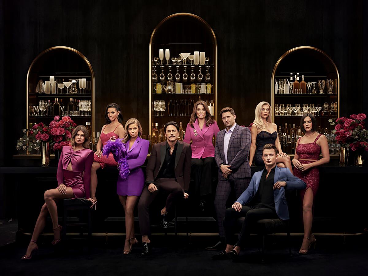 The cast of "Vanderpump Rules" poses in front of a dramatically lit bar.