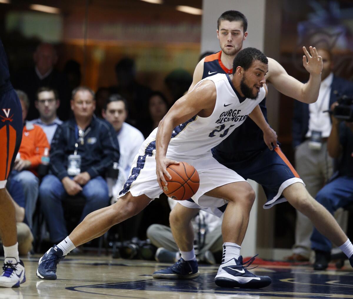 George Washington forward Kevin Larsen (21) drives against Virginia center Mike Tobey (10) during the second half. George Washington upset the No. 6 Cavaliers, 73-68.