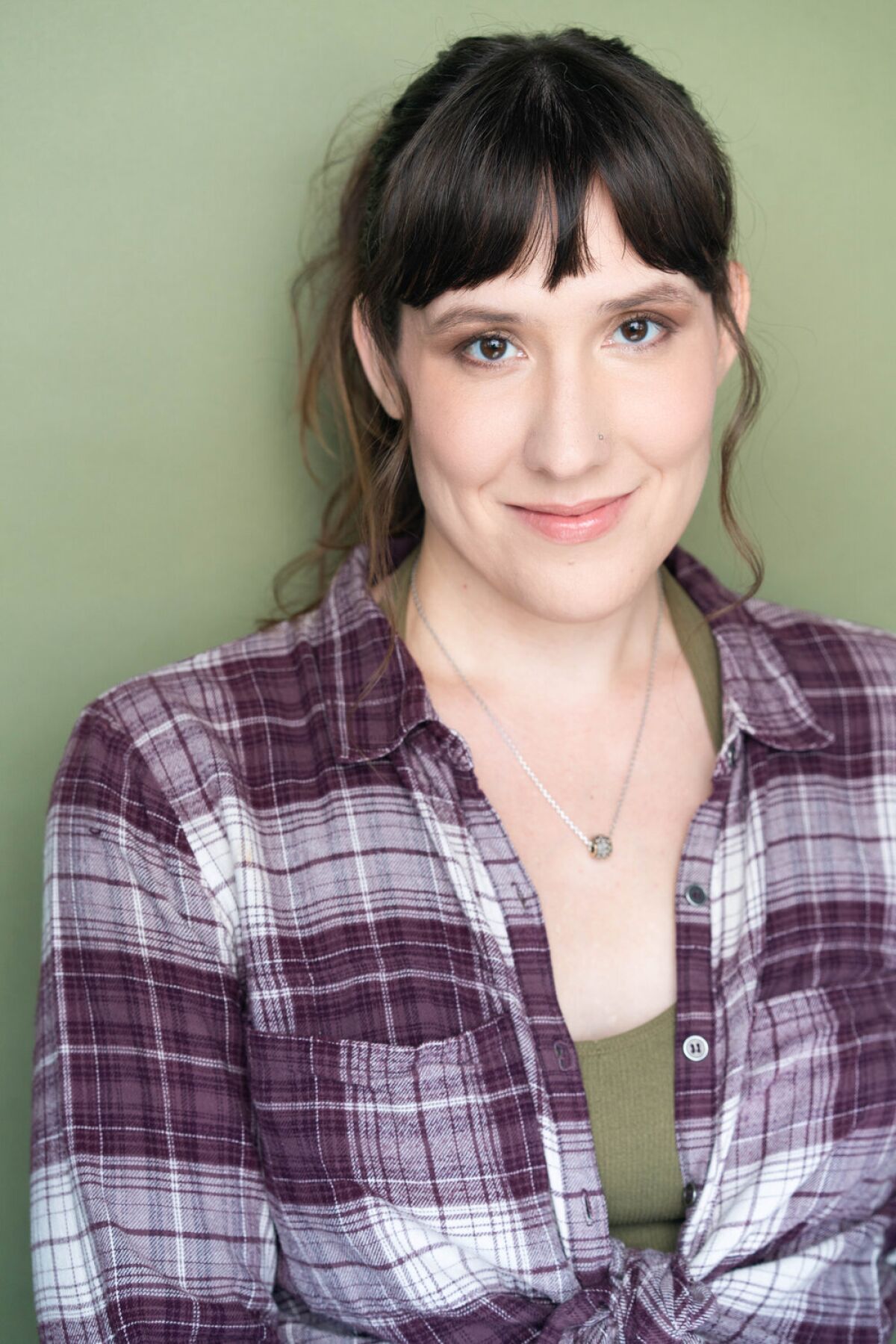 A headshot of a woman wearing a plaid shirt 