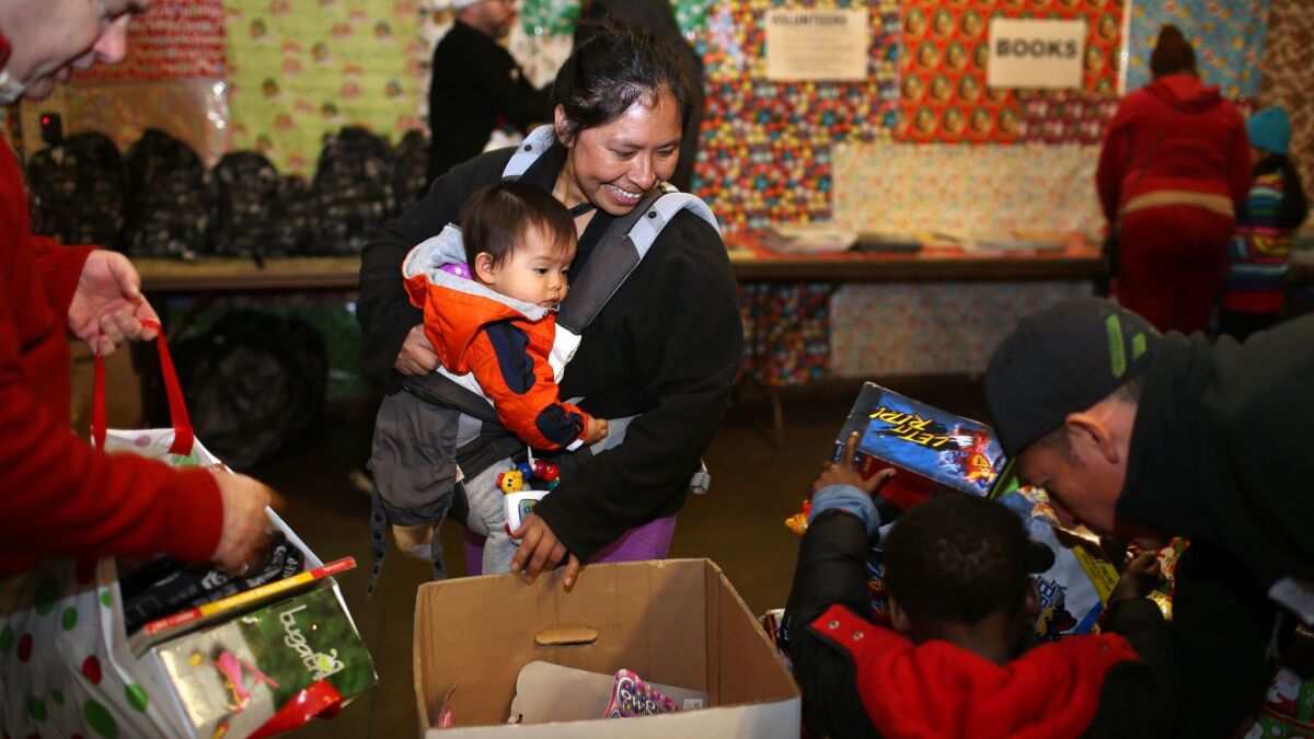 Zarela Lopez carries her 1-year-old daughter, Liesel Shanell Lopez, through a room full of toys to pick up some to take home in 2016.