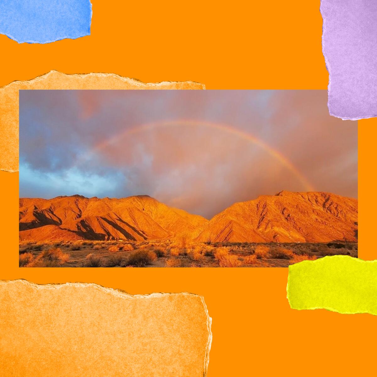 Desert mountains with dark clouds, a bit of blue sky and an orange-y rainbow.