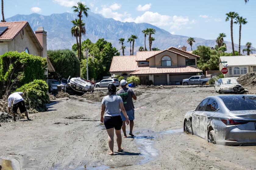 CATHEDRAL CITY, CA - AUGUST 22, 2023: Residents walk towards Horizon Road amid the destruction after tropical storm Hilary sent damaging flood water to the area Sunday night on August 22, 2023 in Cathedral City, California. (Gina Ferazzi / Los Angeles Times)
