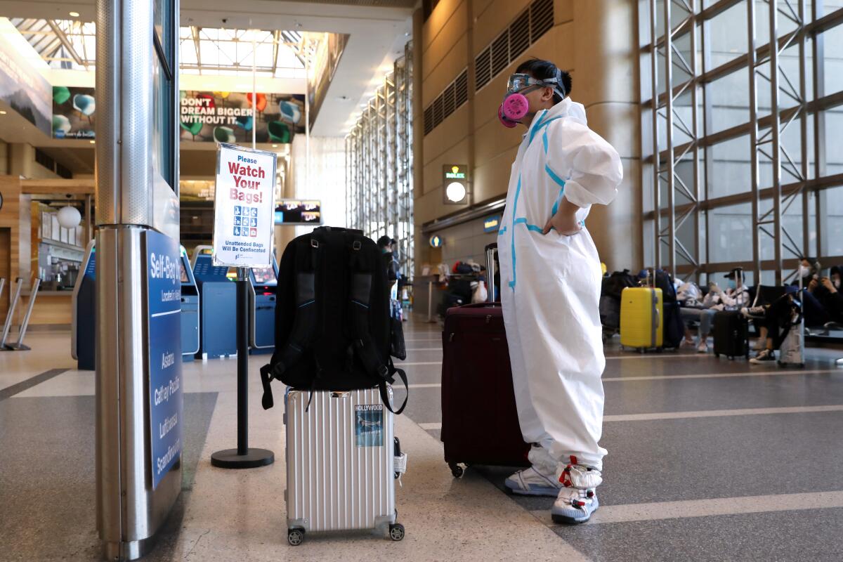 A passenger wearing personal protective equipment checks his flight status in the Tom Bradley International Terminal at Los Angeles International Airport on Wednesday.