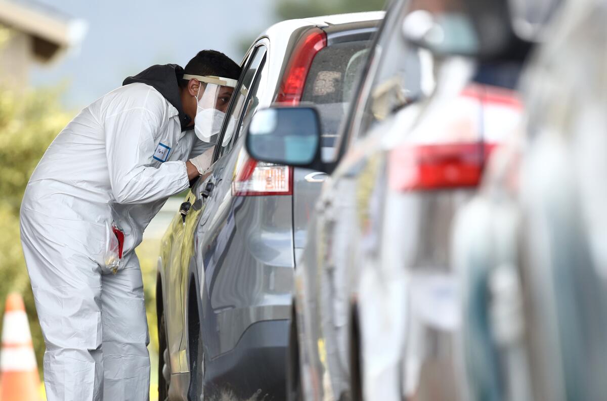 A medical professional administers a coronavirus test at a drive-through location run by staffers from University of California, San Francisco Medical Center (UCSF) in the parking lot of the Bolinas Fire Department.