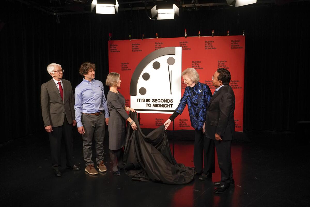 Fire people uncover a giant display showing a clock and the words "It is 90 seconds to midnight." 