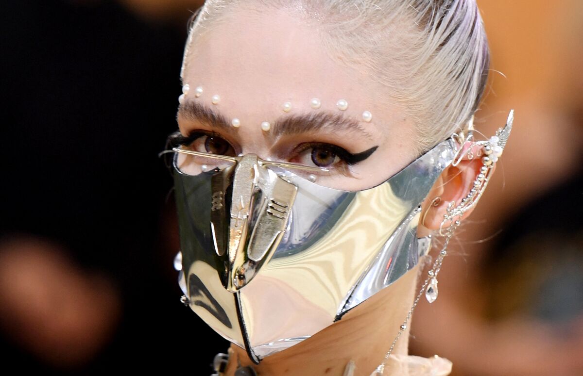 Singer-songwriter Grimes arrives at a gala in a metallic silver mask and jeweled elf ears