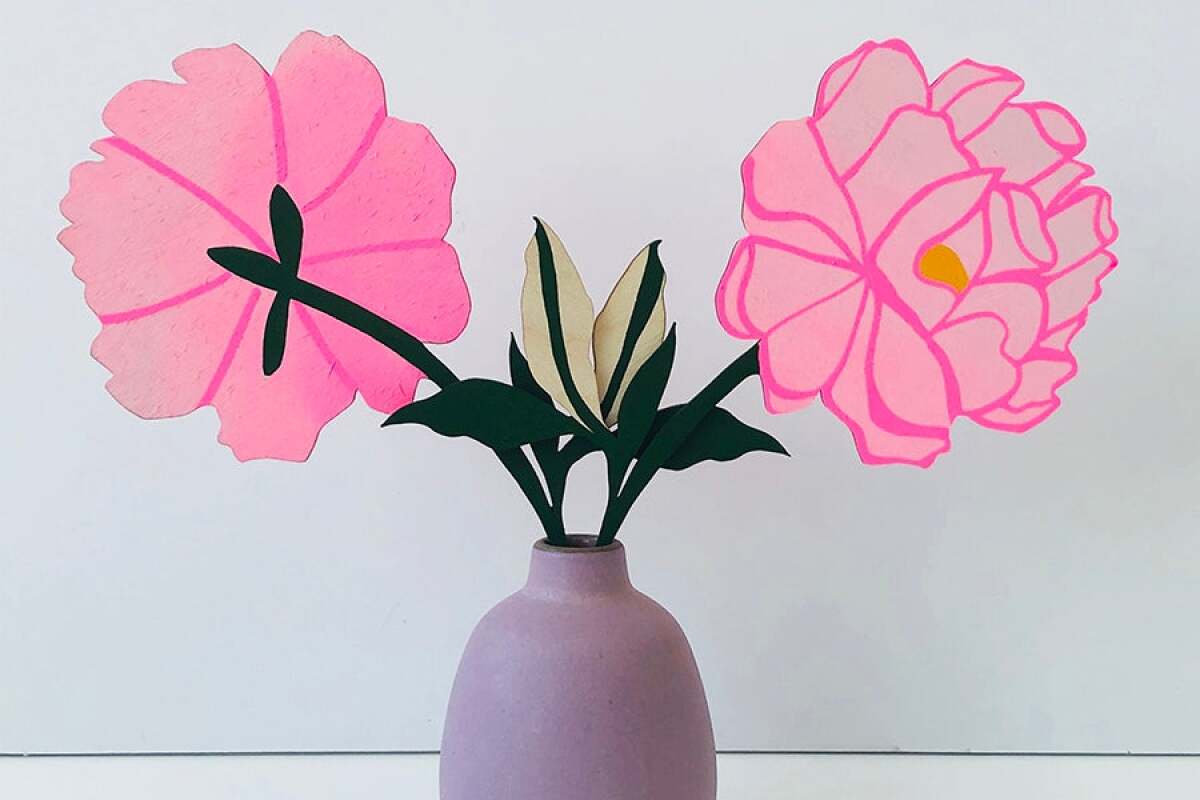 Two  hand-painted pink wooden flowers in a purple vase.