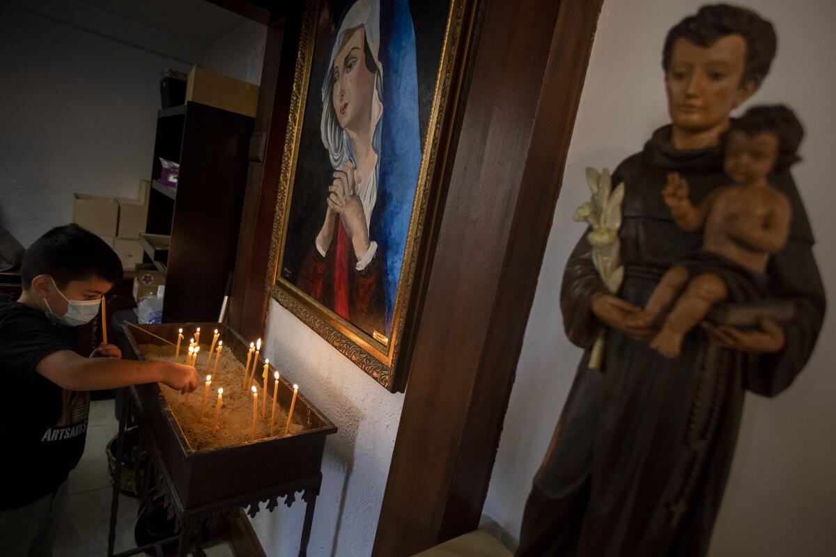 A boy lights a candle at an altar