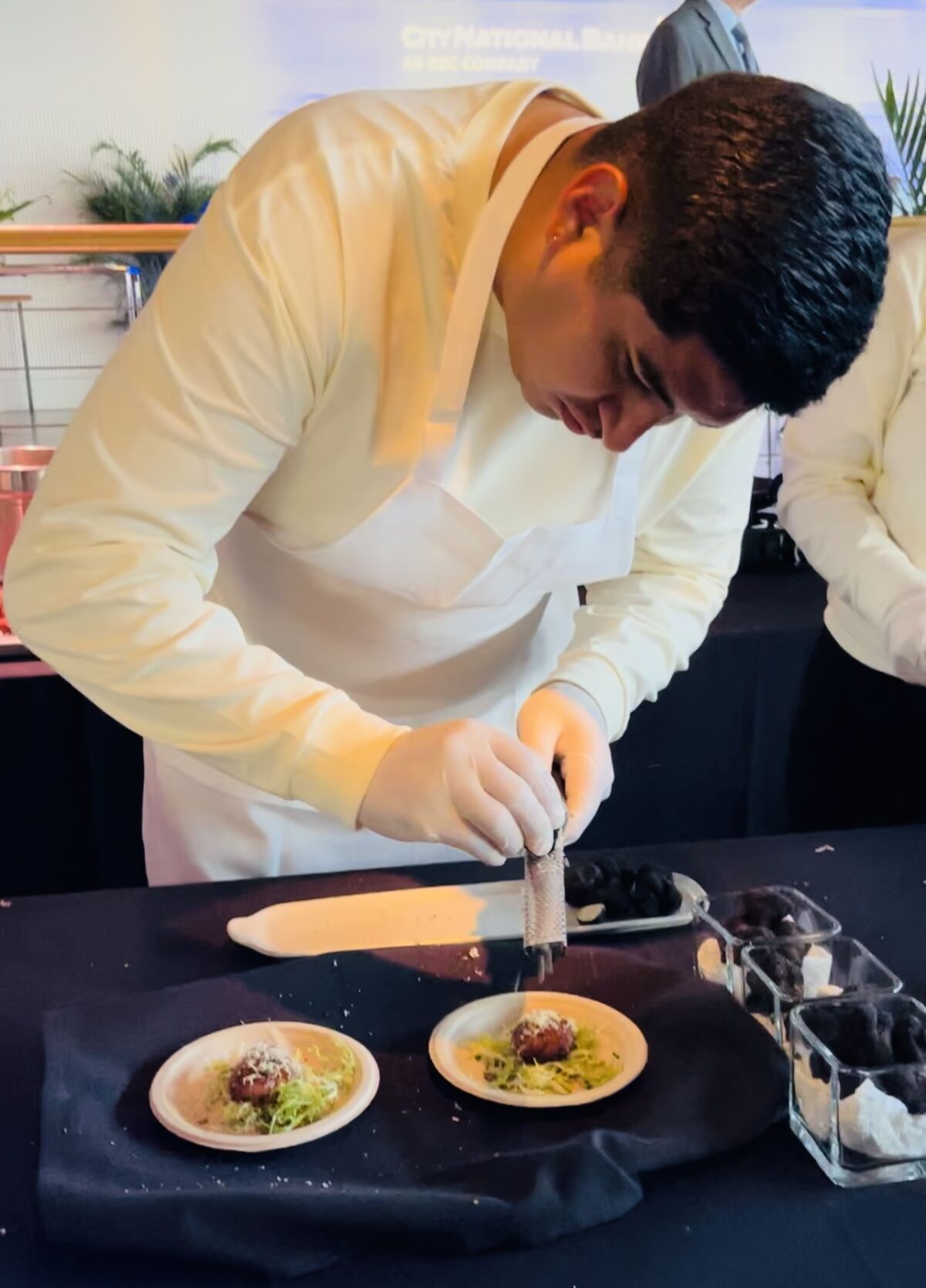 A man bends over a prep table.