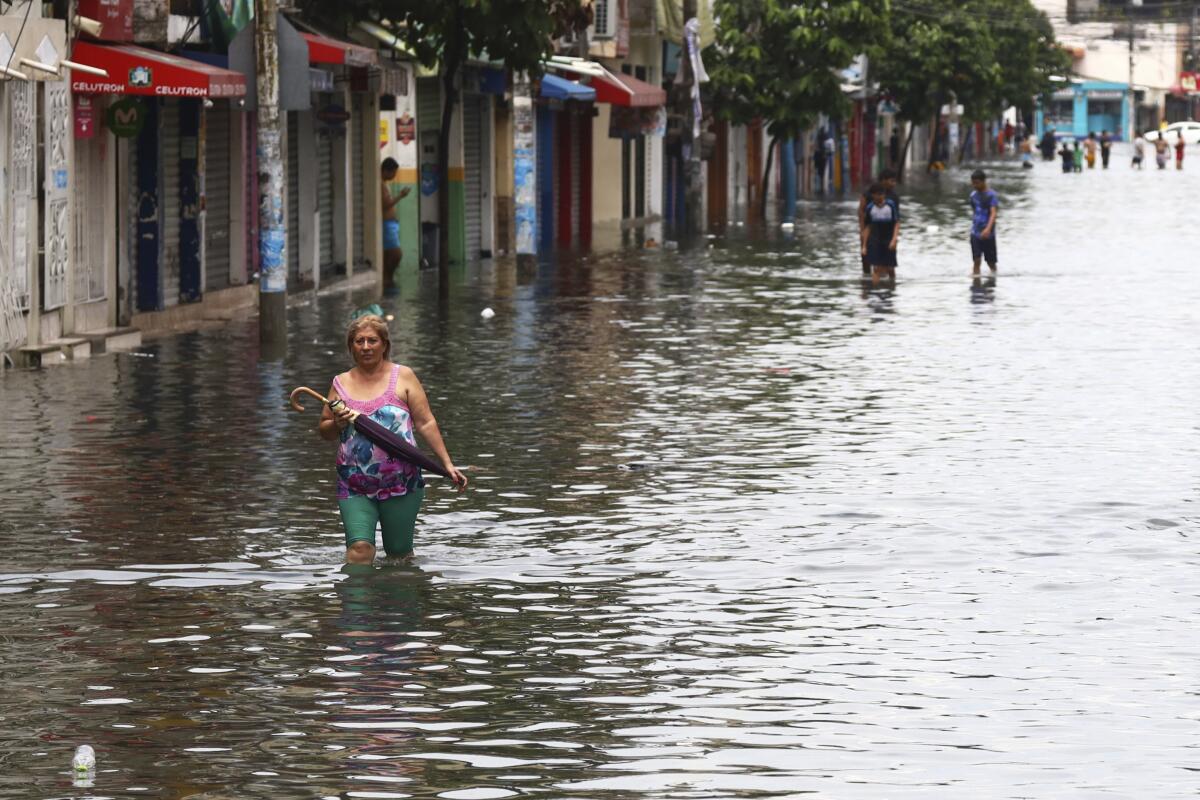 Una mujer avanza por una calle inundada en el vecindario de Sauces, en Guayaquil, Ecuador, 