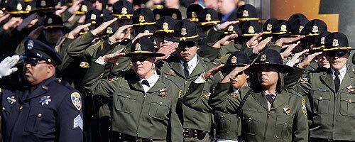 Officers salute the flag-draped caskets of the four slain Oakland police officers at their funeral.