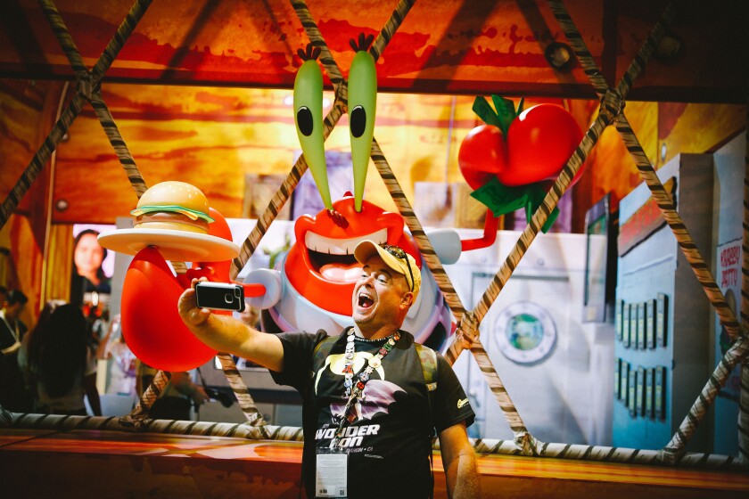 A fan poses with the character Mr. Krabs at Comic-Con in San Diego