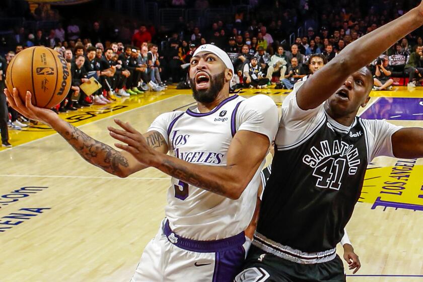 Los Angeles Lakers forward Anthony Davis, left, shoots under pressure from San Antonio Spurs forward Gorgui Dieng.