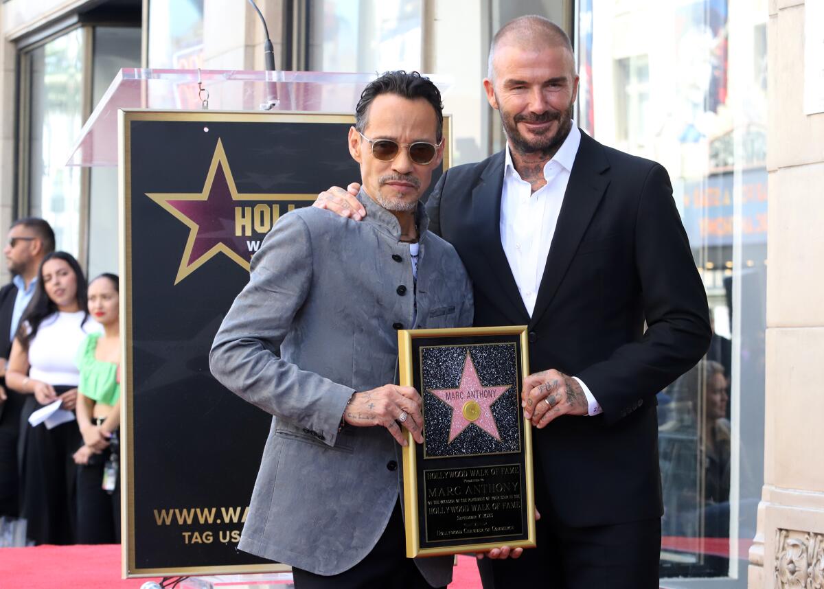 Marc Anthony y el invitado sorpresa David Beckham posan para fotografías mientras 