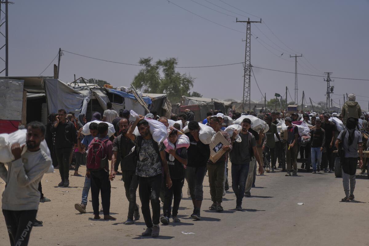 Palestinians carry bags containing food and humanitarian aid packages.