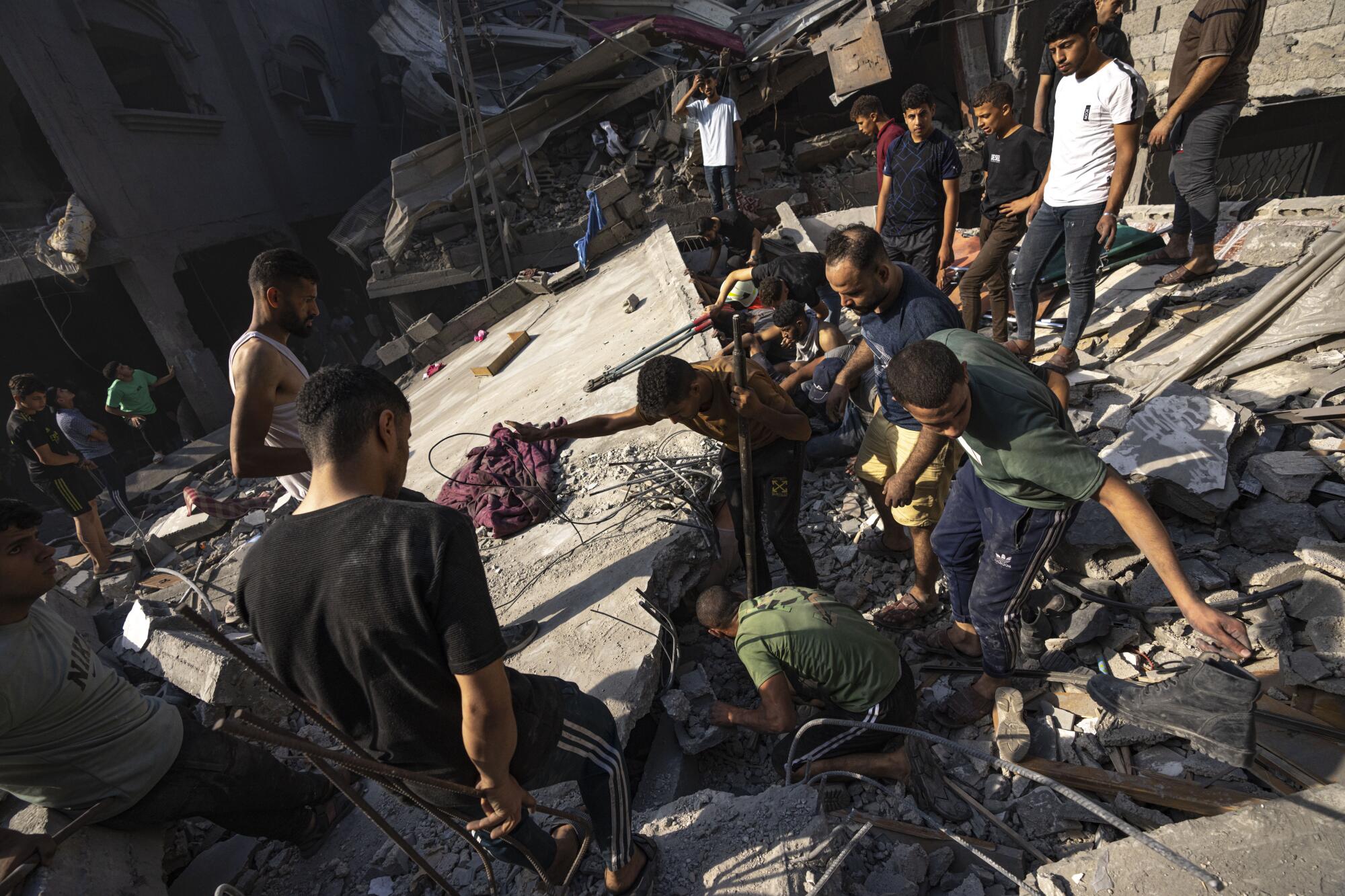 People searching for bodies and survivors in the rubble of a residential building leveled in an Israeli airstrike