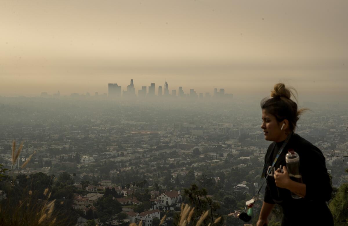 Wildfire smoke hovers over Los Angeles as a jogger runs through Griffith Park.