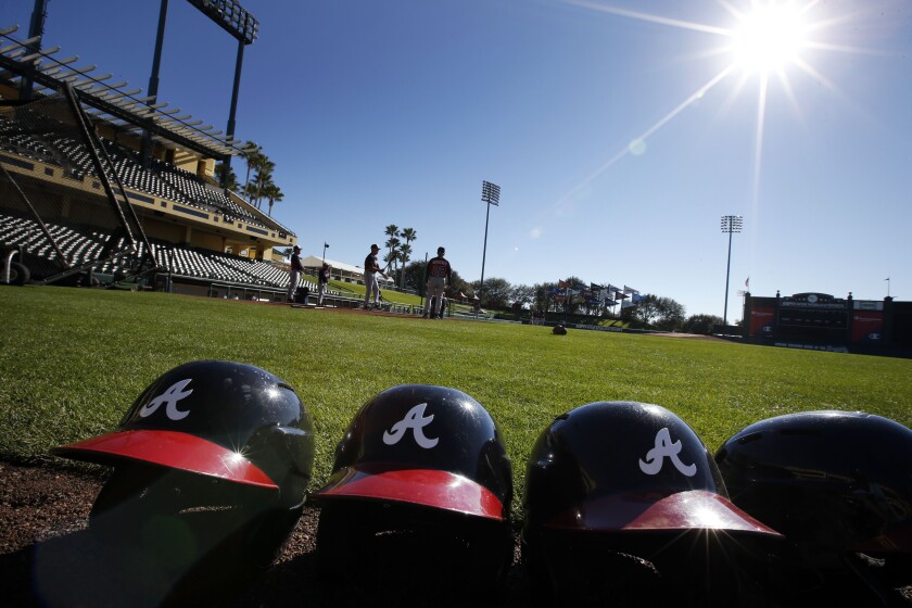 FILE - In this Feb. 18, 2014, file photo, Atlanta Braves batting helmets sits on the field under a shining sun during a spring training baseball workout in Kissimmee, Fla. Major League Baseball revamped its spring training exhibition schedule because of the pandemic, cutting travel for Florida-based teams in an effort to avoid the novel coronavirus, the league announced Friday, Feb. 12, 2021. (AP Photo/Alex Brandon, File)