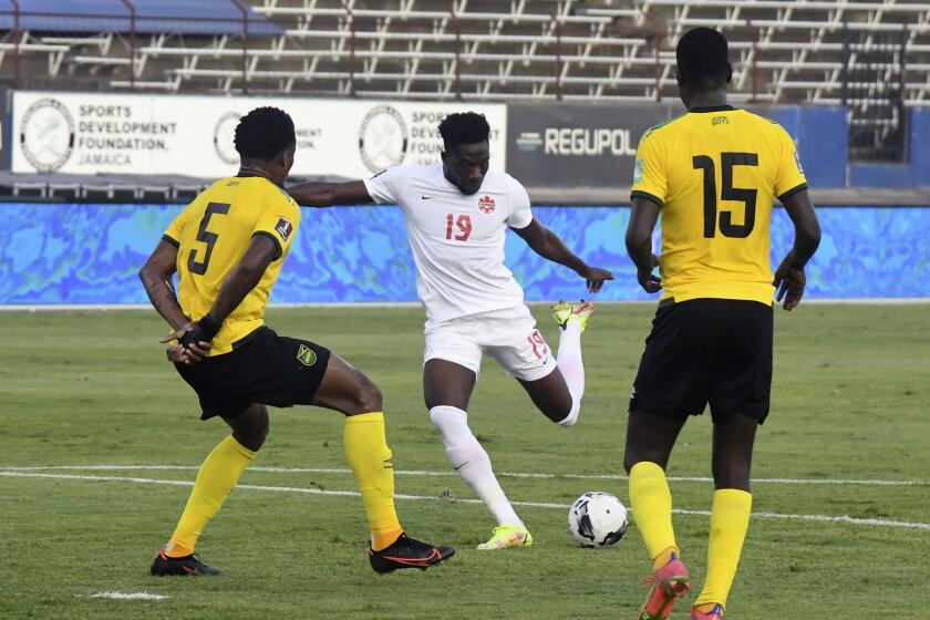 Canada's Alphonso Davies fights for the ball against Jamaica's Alvas Powell and Je-vaughn Watson 