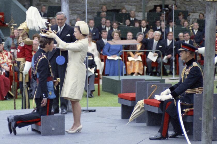 Queen Elizabeth II crowns her son Charles, Prince of Wales during his investiture ceremony on July 1, 1969 at Caernarfon Castle in Wales. Prince Philip the Duke of Edinburgh is seated at right. Britain's Home Secretary James Callaghan looks on. (AP Photo)