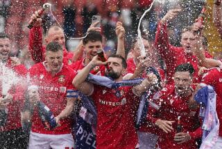 Wrexham players on the pitch celebrating promotion to League One after the final whistle.