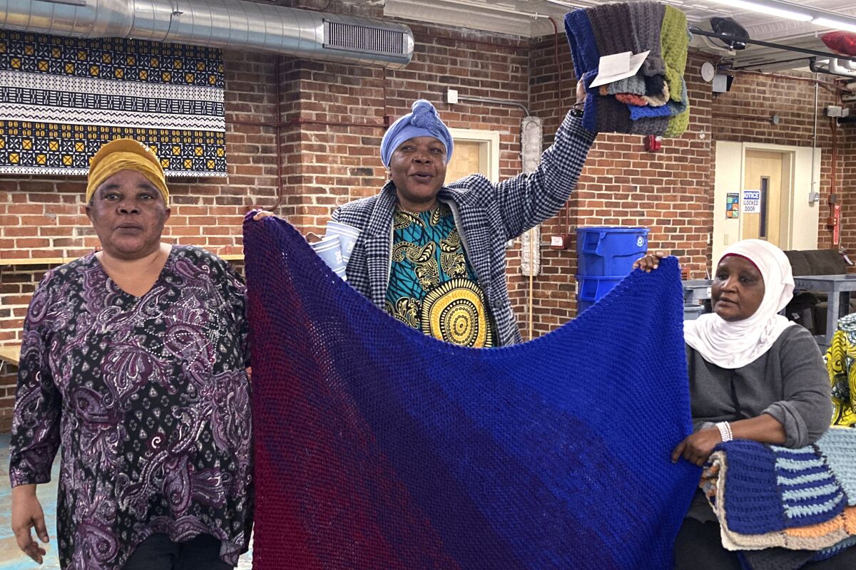 Mochozi Bigelegele, left, and Martha Mlebinge, center, both originally from Congo, and Fatuma Hussein, right, originally from Burundi, hold handmade blankets they picked out at a Welcome Blanket giveaway event on March 21, 2023, in Burlington, Vt. The blankets were made by Vermont and out-of-state crafters as gifts for refugees to welcome them to the community as part of the national Welcome Blanket project. (AP Photo/Lisa Rathke)