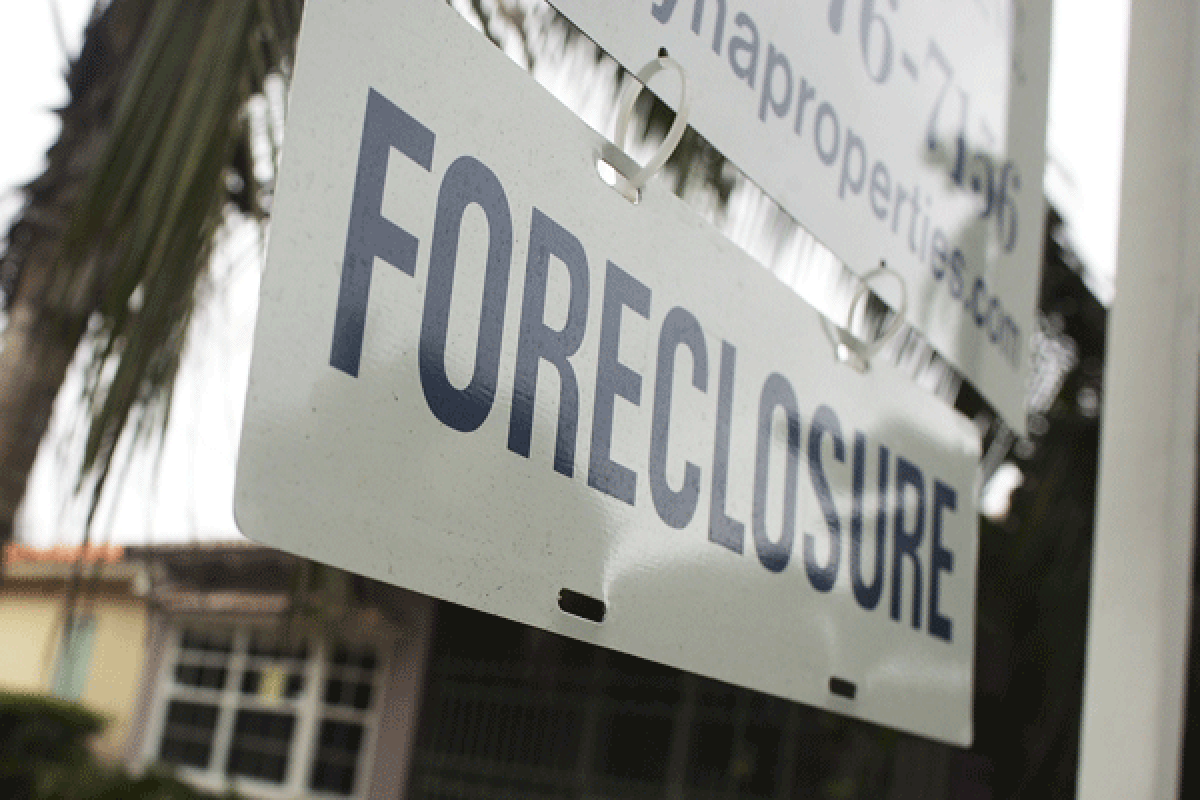 A foreclosure sign hangs in front of a house.