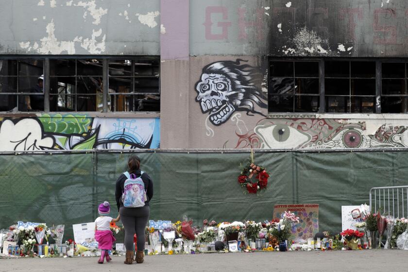 FILE - Flowers, pictures, signs and candles, are placed at the scene of a warehouse fire which killed dozens in Oakland, Calif. Dec. 13, 2016. The converted artists' warehouse that was acquired by The Unity Council, a nonprofit community development organization, was quietly razed in May 2023, in preparation for possible development into badly needed low-income housing. (AP Photo/Marcio Jose Sanchez, File)