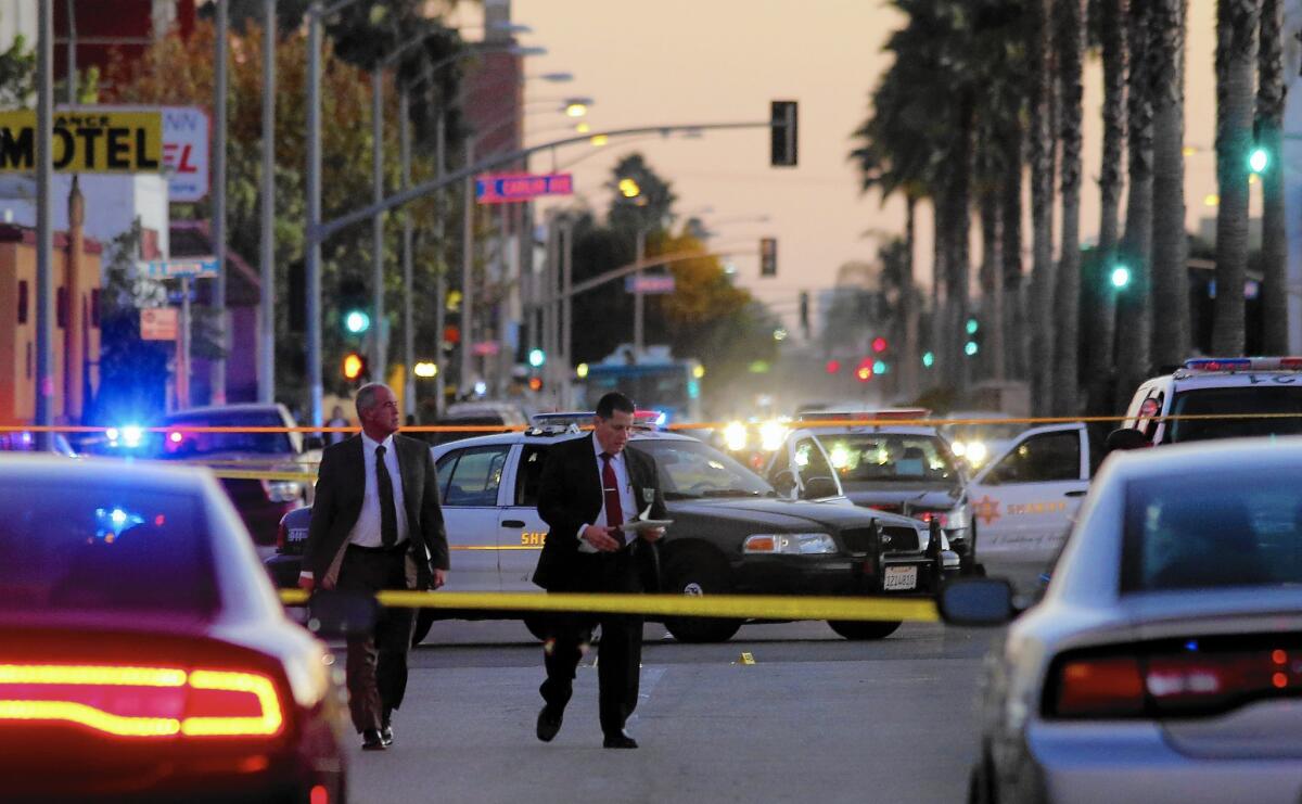 Law enforcement officials investigate the area where sheriff's deputies fatally shot a man outside a Lynwood gas station. The incident was recorded on video.