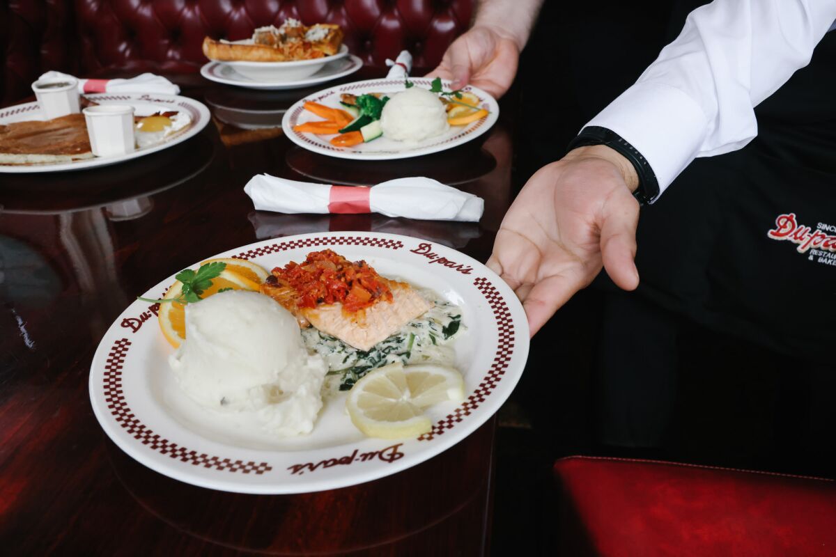 A hand places a plate of food on a table