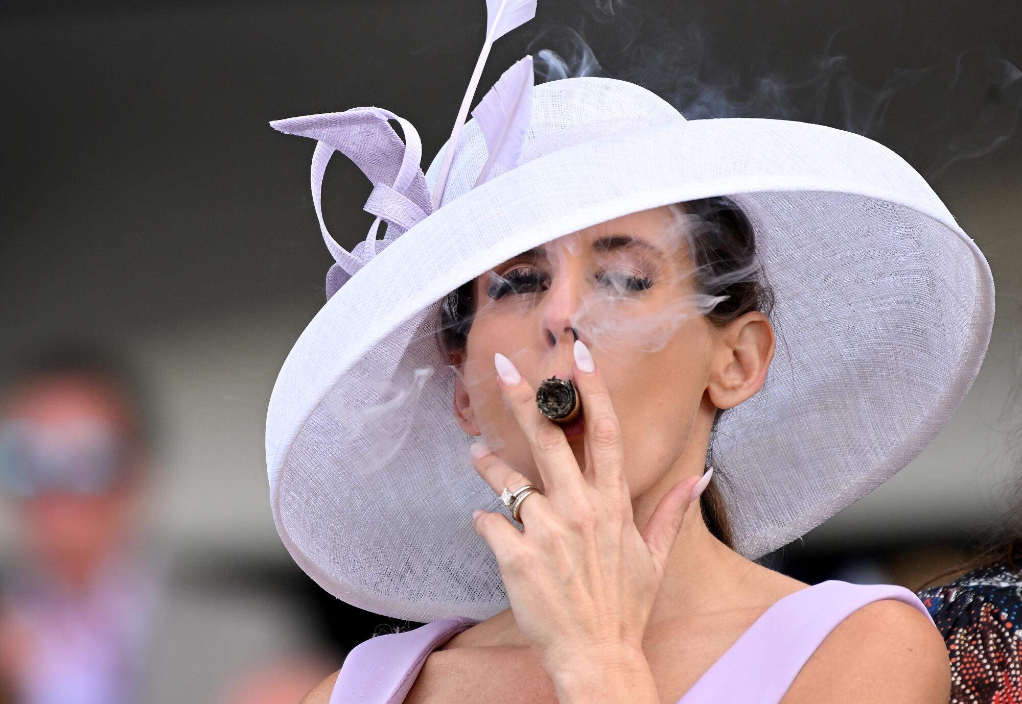 Los espectadores usan sombreros elegantes y cigarros grandes en el Breeders' Cup Classic en el Parque Santa Anita en noviembre.