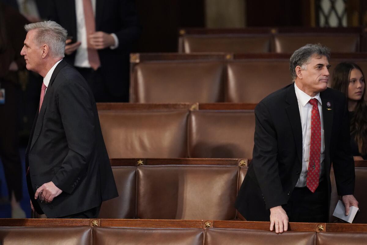 Two men walking in opposite directions among the seats in House of Representatives 