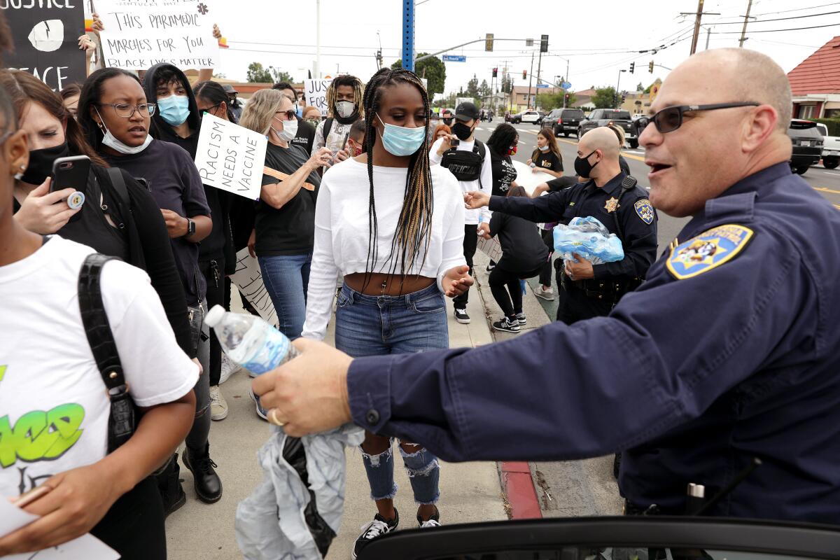 California Highway Patrol Captain of the Santa Fe Springs station, David Moeller, right, hands out water to demonstrators during a peaceful protest in Cerritos.
