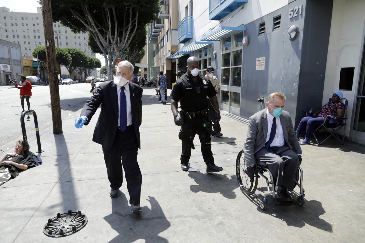 U.S. District Court Judge David O. Carter walks skid row with LAPD Officer Deon Joseph and the Rev. Andy Bales
