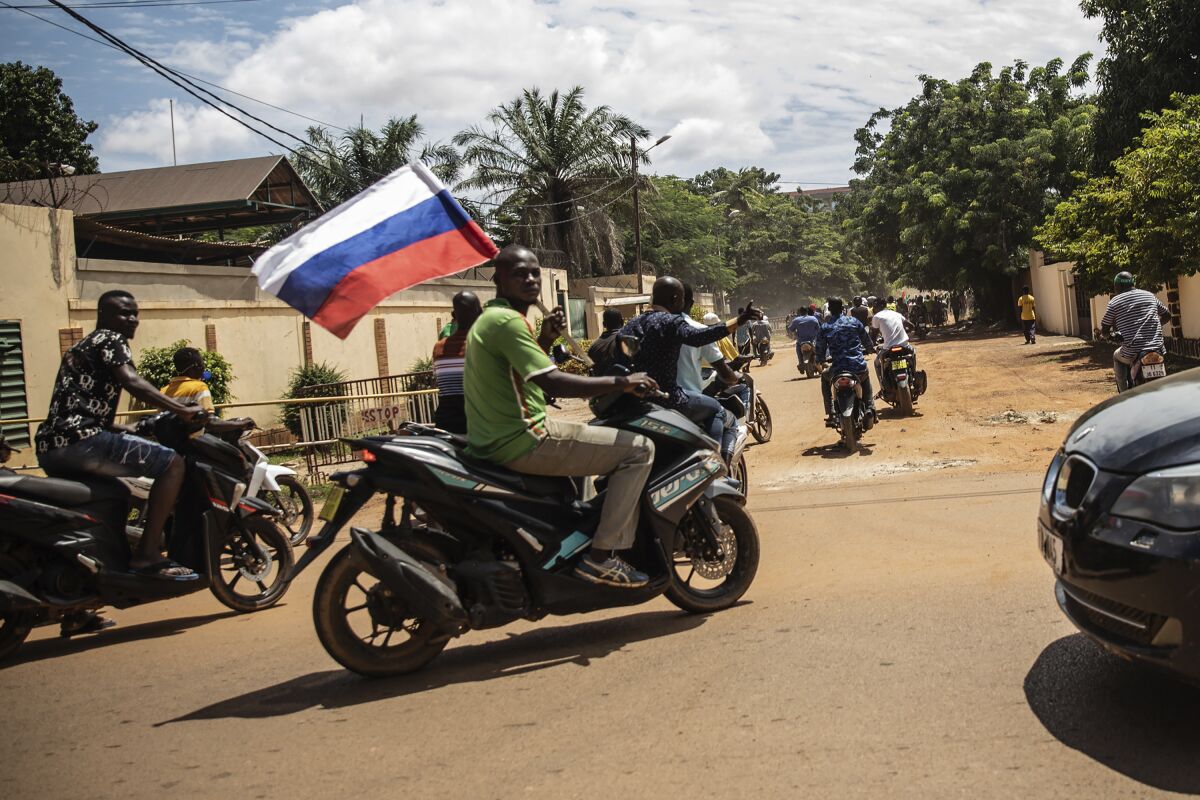 Supporters of Capt. Ibrahim Traore parade waving a Russian flag in the streets of Ouagadougou, Burkina Faso, Sunday, Oct. 2, 2022. Burkina Faso's new junta leadership is calling for calm after the French Embassy and other buildings were attacked. The unrest following the West African nation's second coup this year came after a junta statement alleged that the ousted interim president was at a French military base in Ouagadougou. France vehemently denied the claim and has urged its citizens to stay indoors amid rising anti-French sentiment in the streets. (AP Photo/Sophie Garcia)