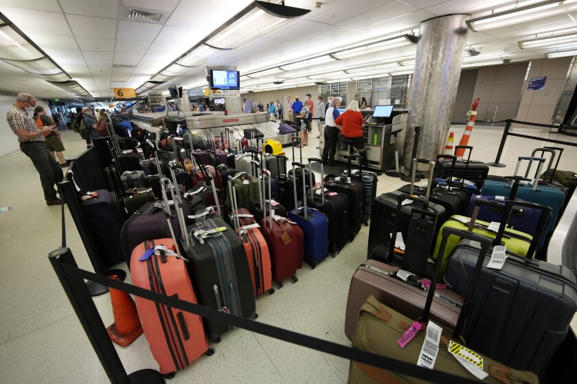 Baggage stacks up from delayed travellers in the baggage claim area in Denver International Airport Wednesday, June 16, 2021, in Denver. The Biden administration is planning to require that airlines refund fees on checked baggage if the bags get seriously delayed. The proposal would also require refunds for fees on extras like internet access if the airline fails to provide the service during the flight. (AP Photo/David Zalubowski)