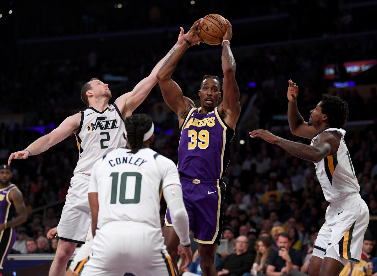 Lakers' Dwight Howard (39) grabs a rebound in front of Utah Jazz's Ed Davis (17) and Mike Conley (10), as he is fouled by Joe Ingles (2), during the first half at Staples Center on Friday.