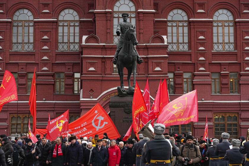 Simpatizantes del Partido Comunista con banderas rojas se congregan en torno de la estatua del mariscal Georgy Zhukov después de colocar una ofrenda floral en la tumba del soldado desconocido en el 80 aniversario de la victoria soviética contra los nazis en la batalla de Stalingrado, Moscú, jueves 2 de febrero de 2023. (AP Foto/Alexander Zemlianichenko)