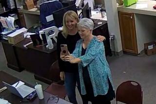 In this Jan. 7, 2021, image taken from Coffee County, Ga., security video, Cathy Latham (right) appears to take a selfie with a member of a computer forensics team inside the local elections office. Latham was the county Republican Party chair at the time. The computer forensics team was at the county elections office in Douglas, Ga., to make copies of voting equipment in an effort that documents show was arranged by Sidney Powell and others allied with then-President Donald Trump. (Coffee County, Georgia via AP)
